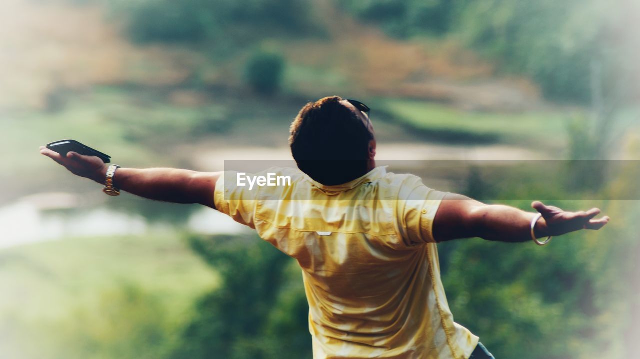 Rear view of woman with arms outstretched standing against sky