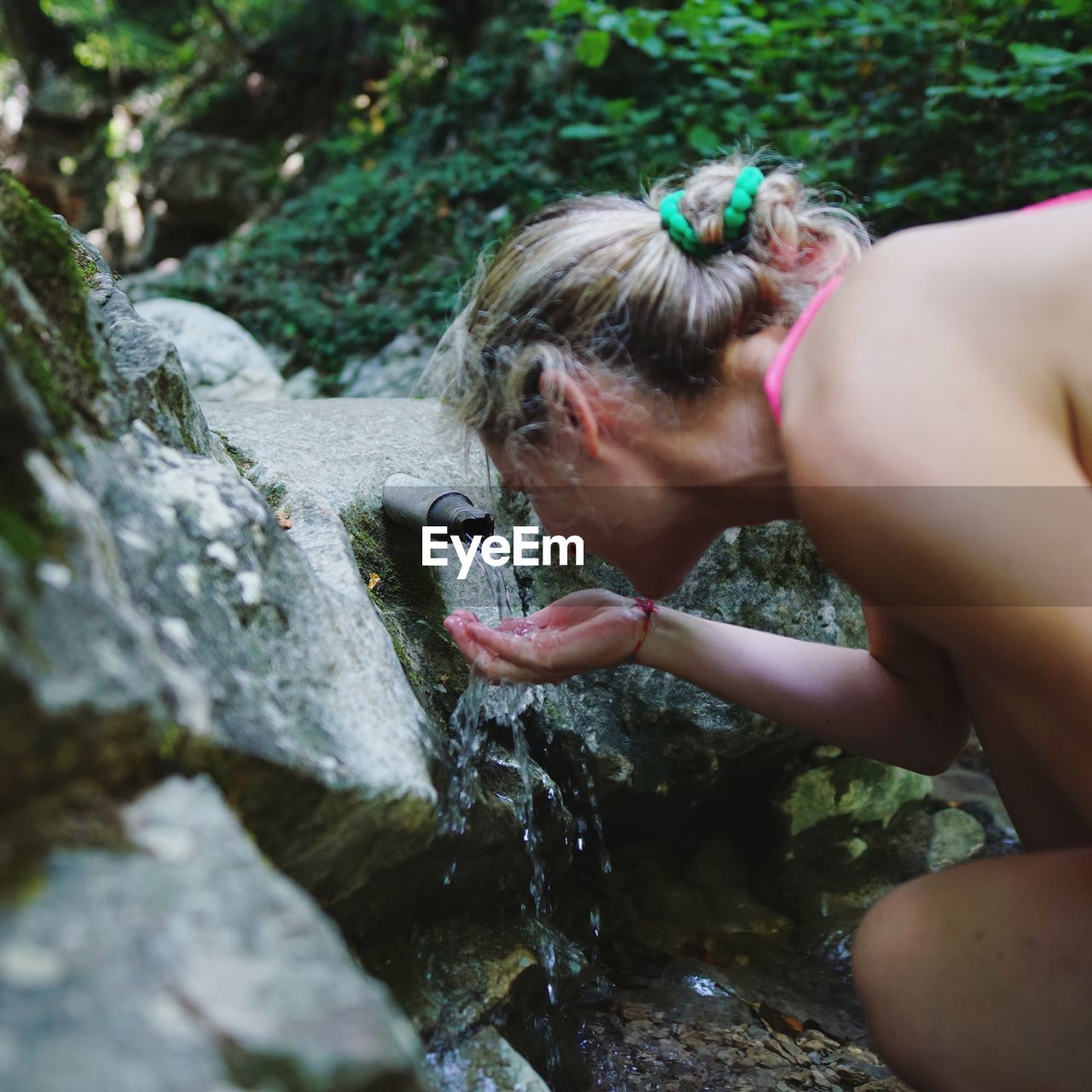Side view of young woman drinking water in forest
