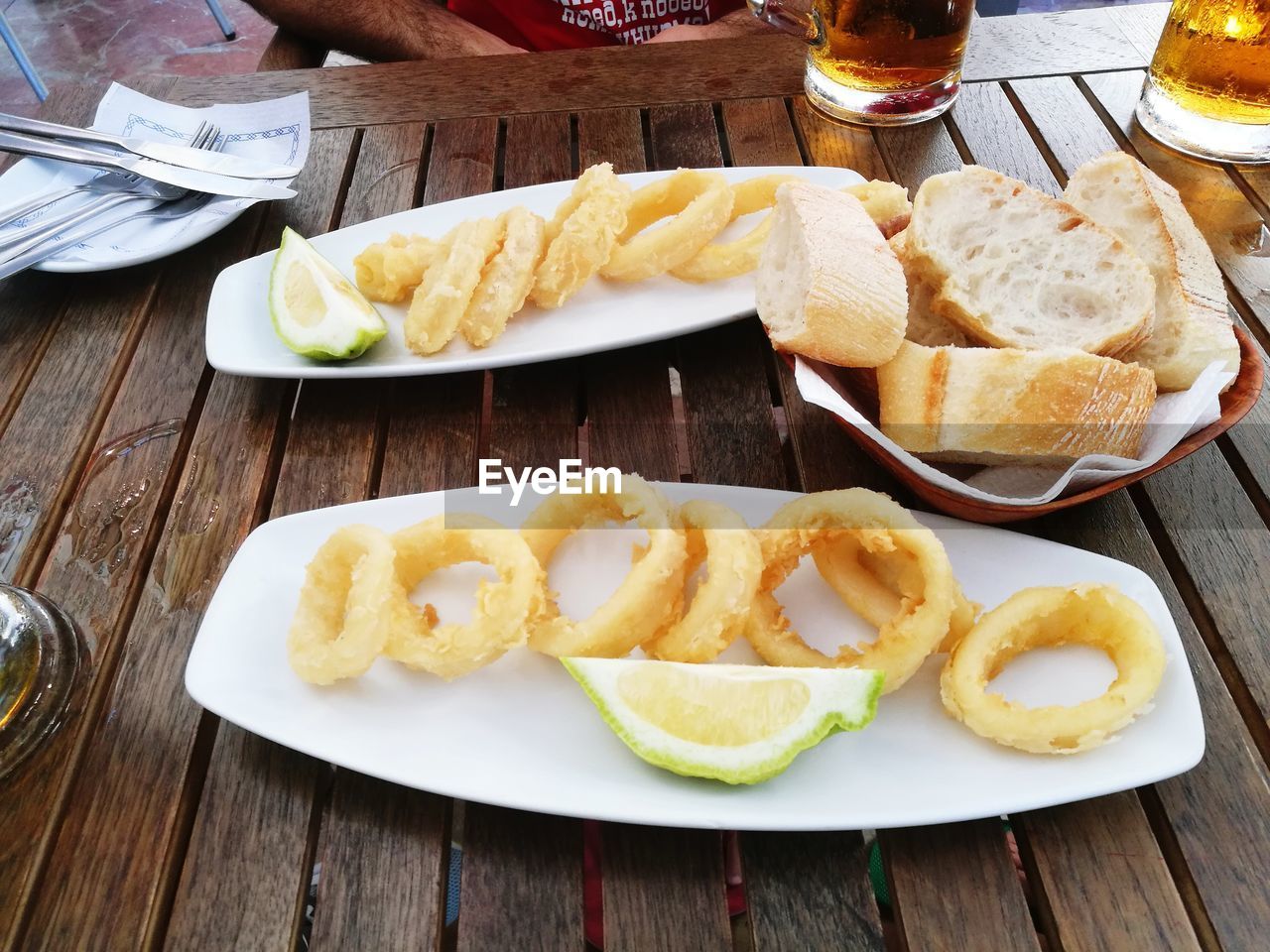 High angle view of onion rings with lime slices in plate and bread on table