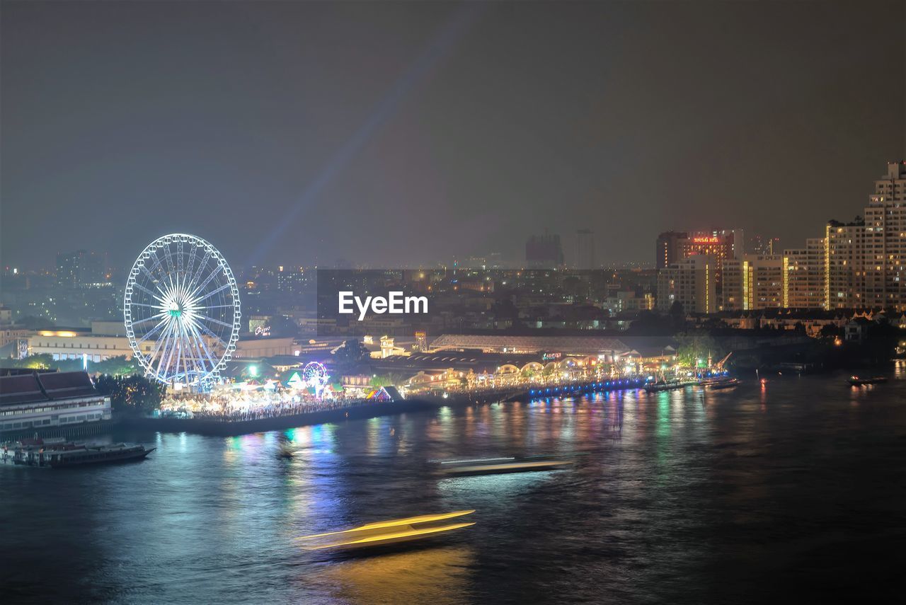 ILLUMINATED FERRIS WHEEL IN CITY AT NIGHT