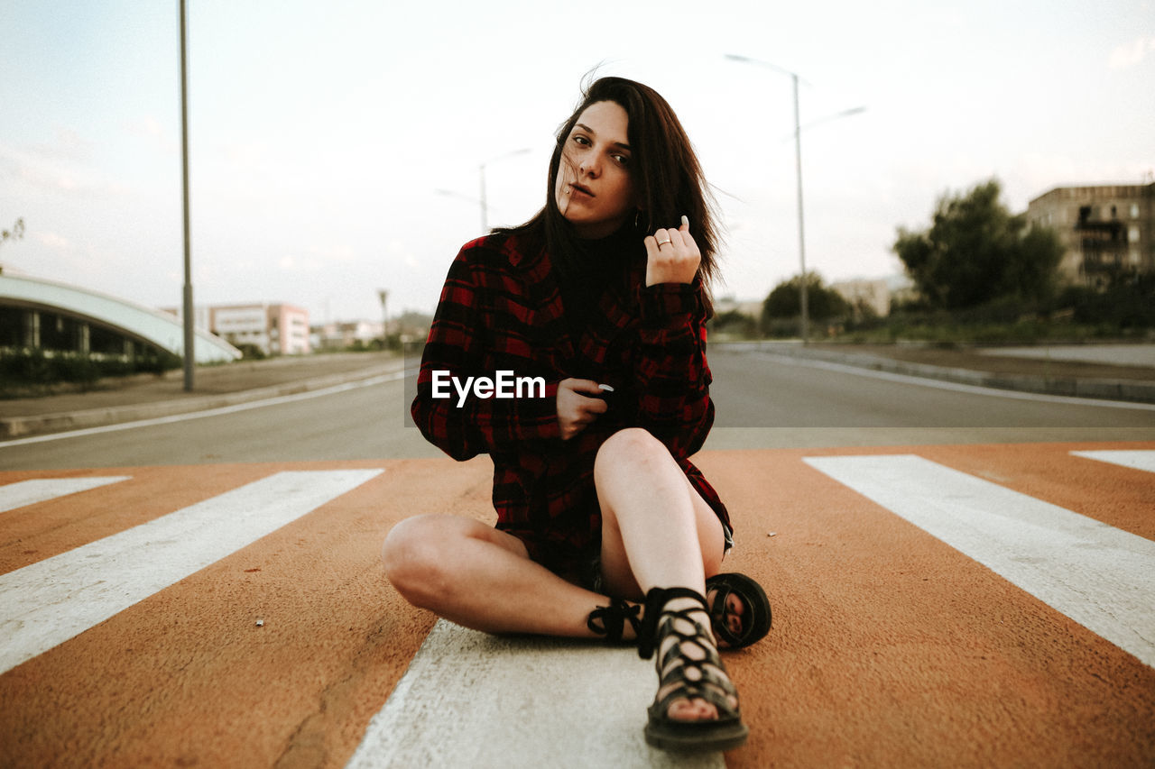 Portrait of young woman sitting on road