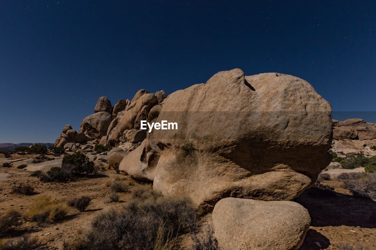 Rocks in desert against blue sky at night