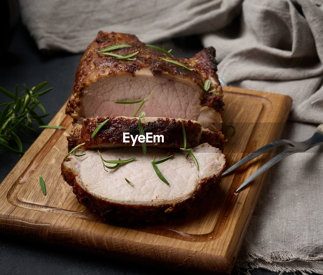 Baked piece of pork meat in spices on a wooden board, cut into pieces. eye of round roast steak