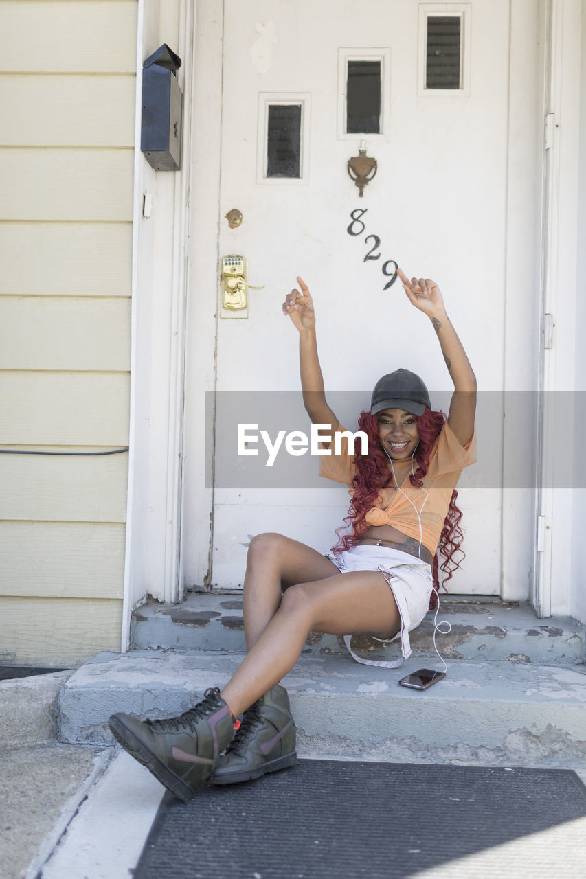 Young woman listening to music at her front door