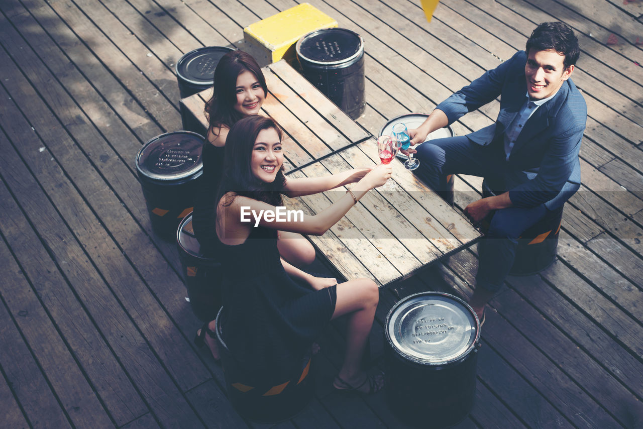 Portrait of happy friends toasting drinks at bar