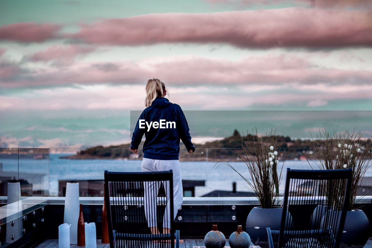 Rear view of woman standing on building terrace against sky