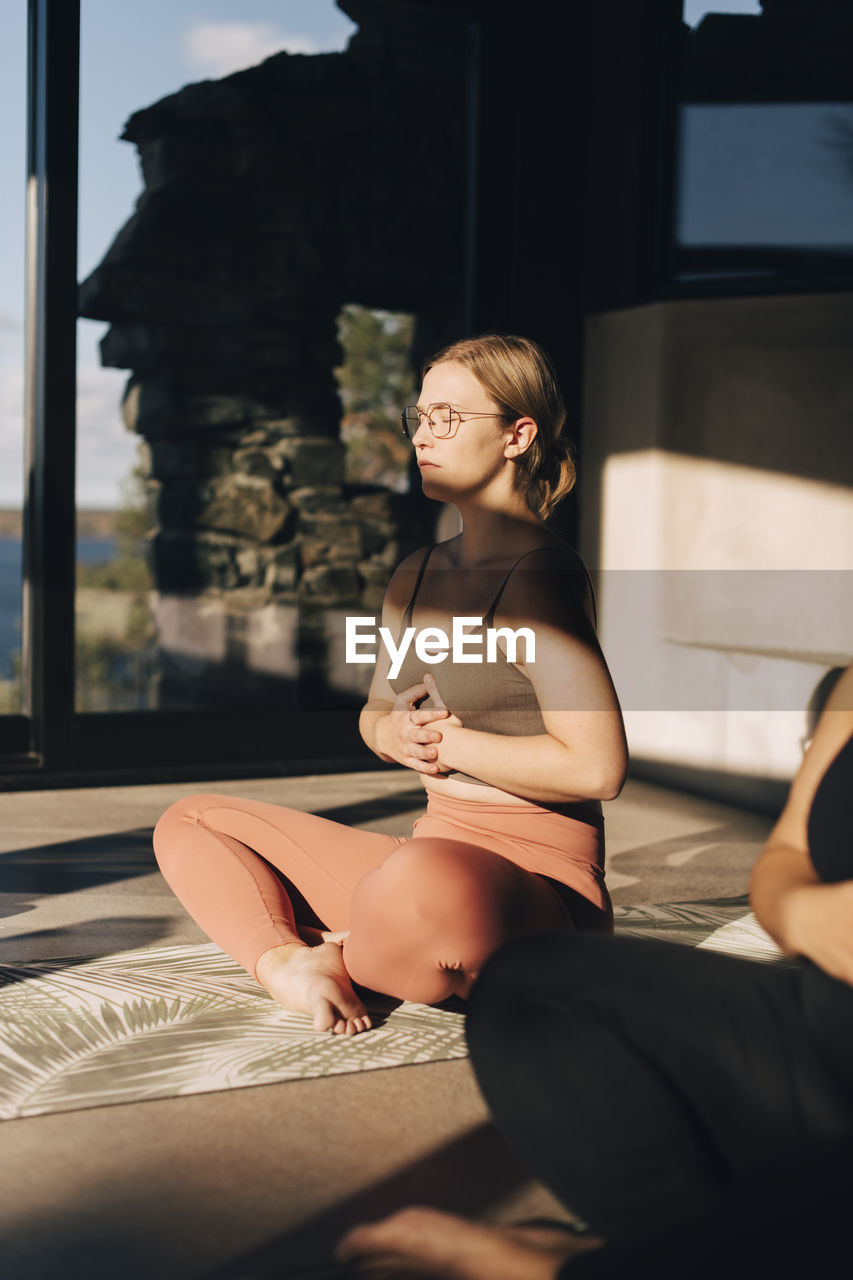 Woman with hands on stomach practicing breathing exercise sitting cross-legged at retreat center