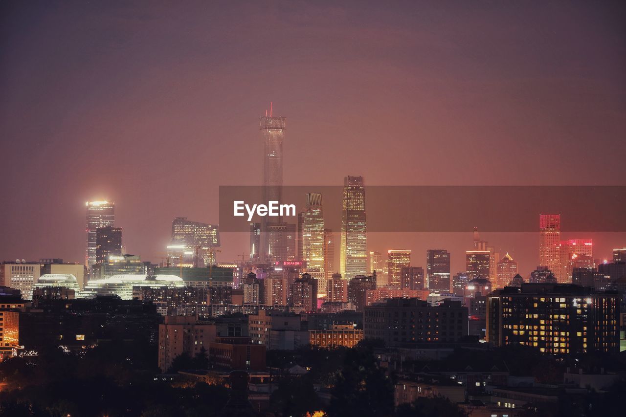 Illuminated buildings in city against sky at night