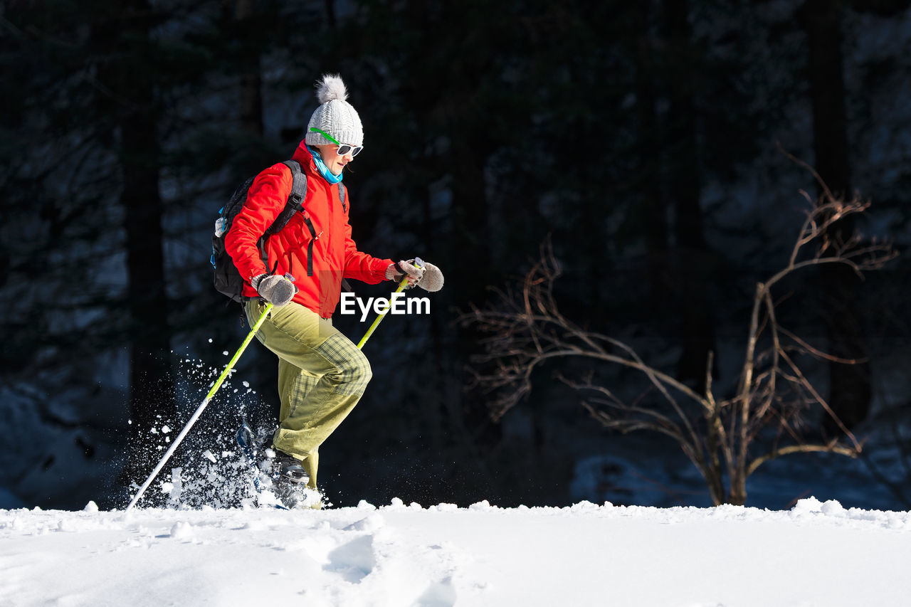 Woman walking on snow covered land against forest