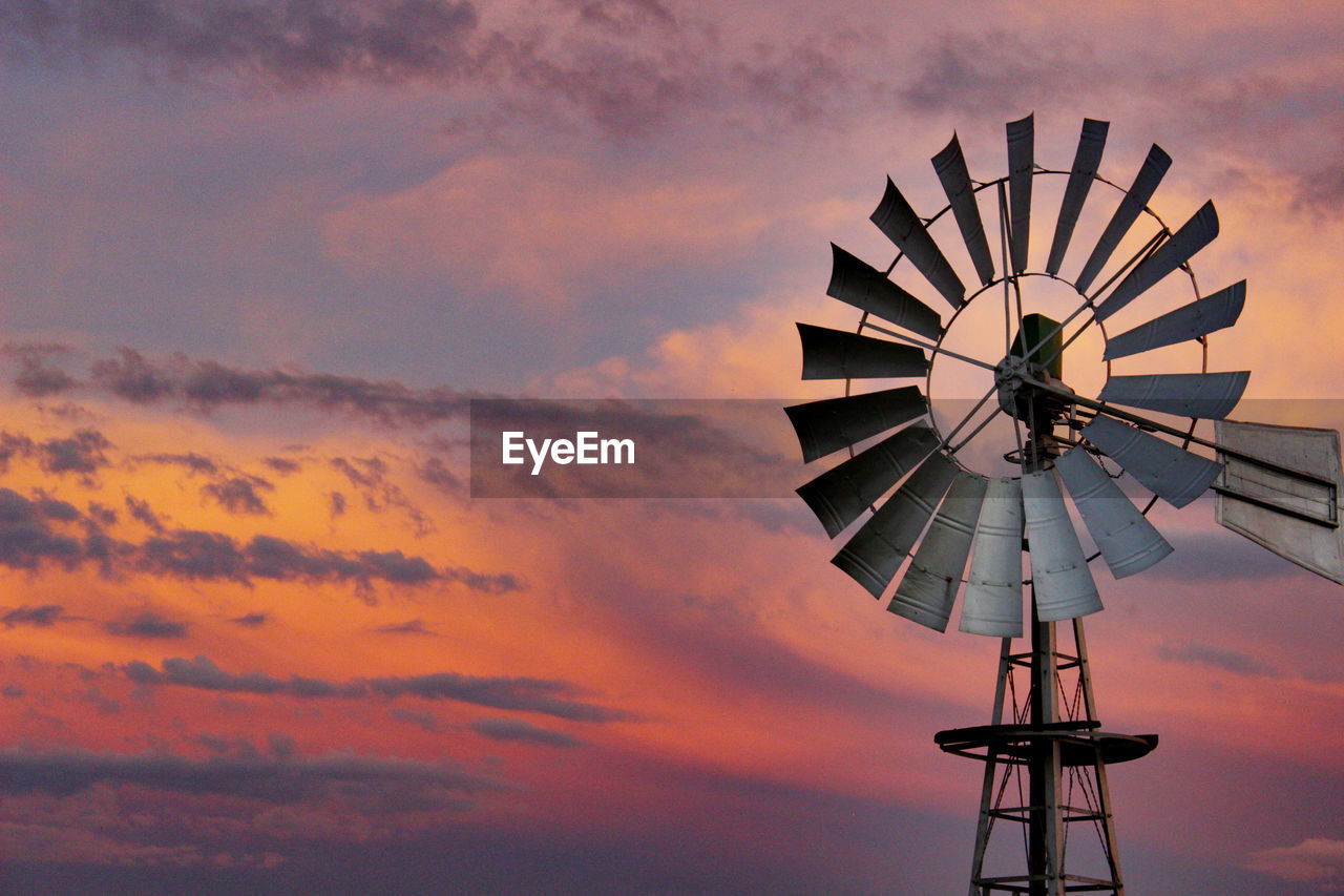 LOW ANGLE VIEW OF WINDMILLS AGAINST SKY DURING SUNSET