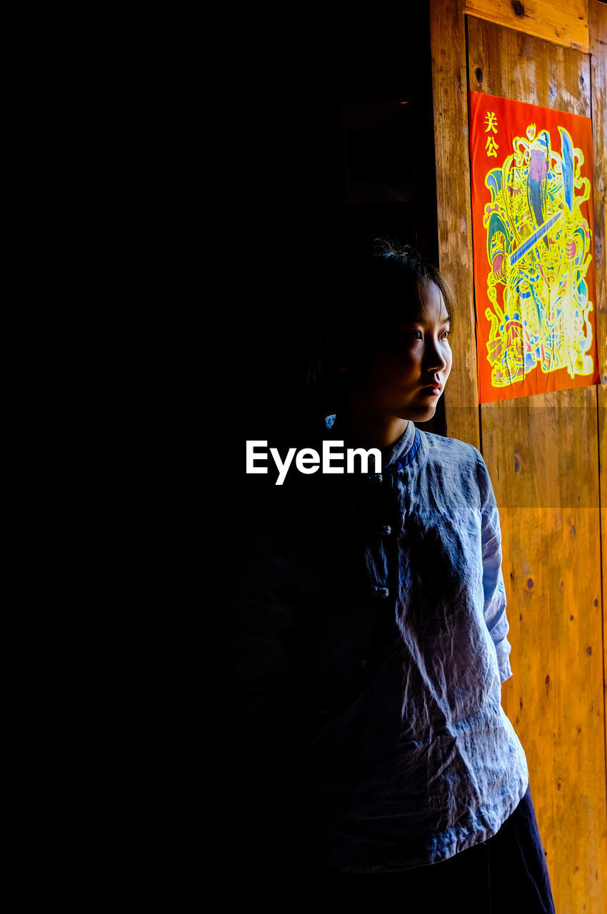 Woman standing by wall at home