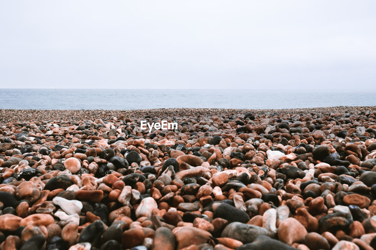 Pebbles on beach against clear sky