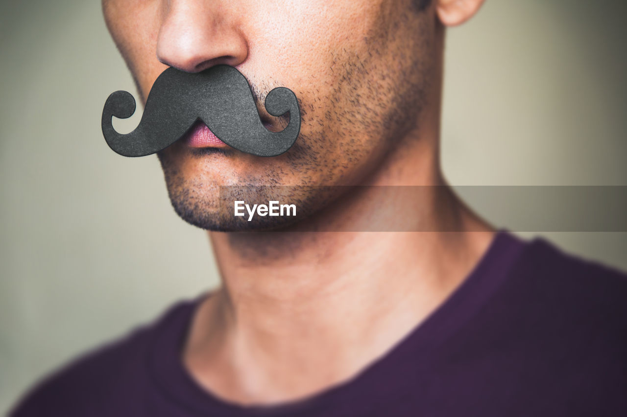 Close up of a man's chin wearing a fake paper made mustache - movember