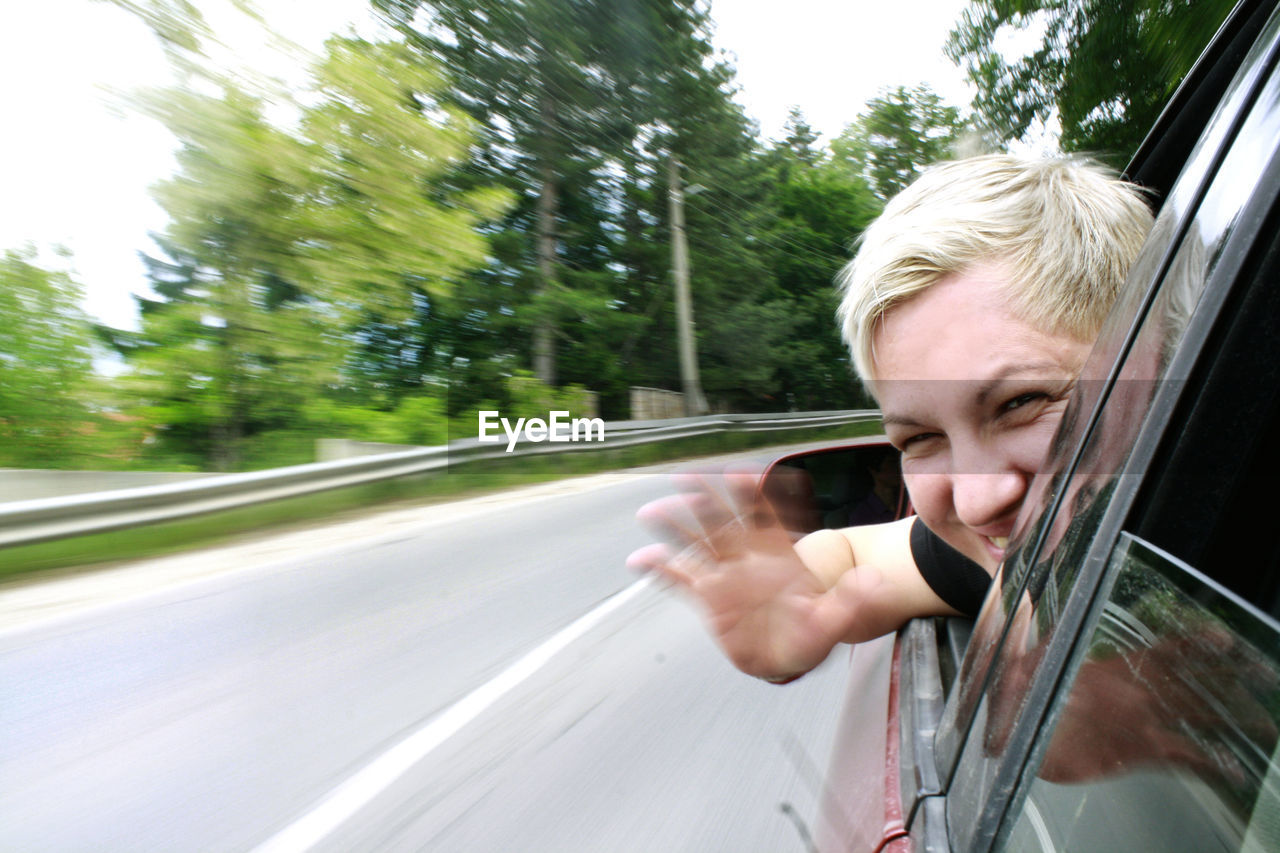 Close-up portrait of cheerful woman looking through car window