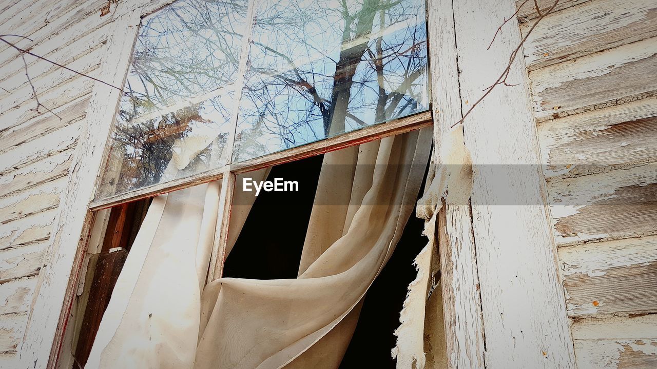 LOW ANGLE VIEW OF ABANDONED HOUSE WINDOW