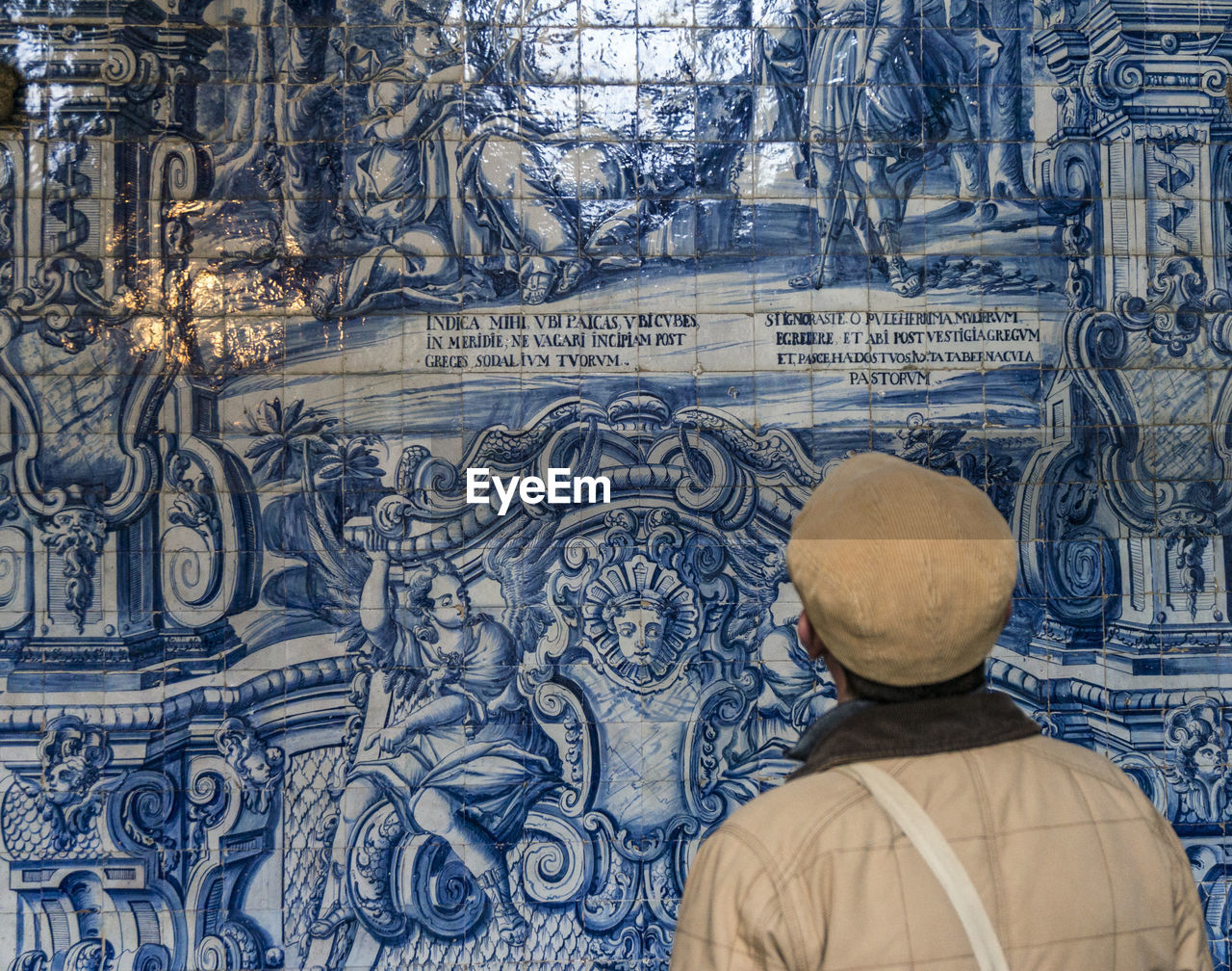 Rear view of man looking at mural in historic building