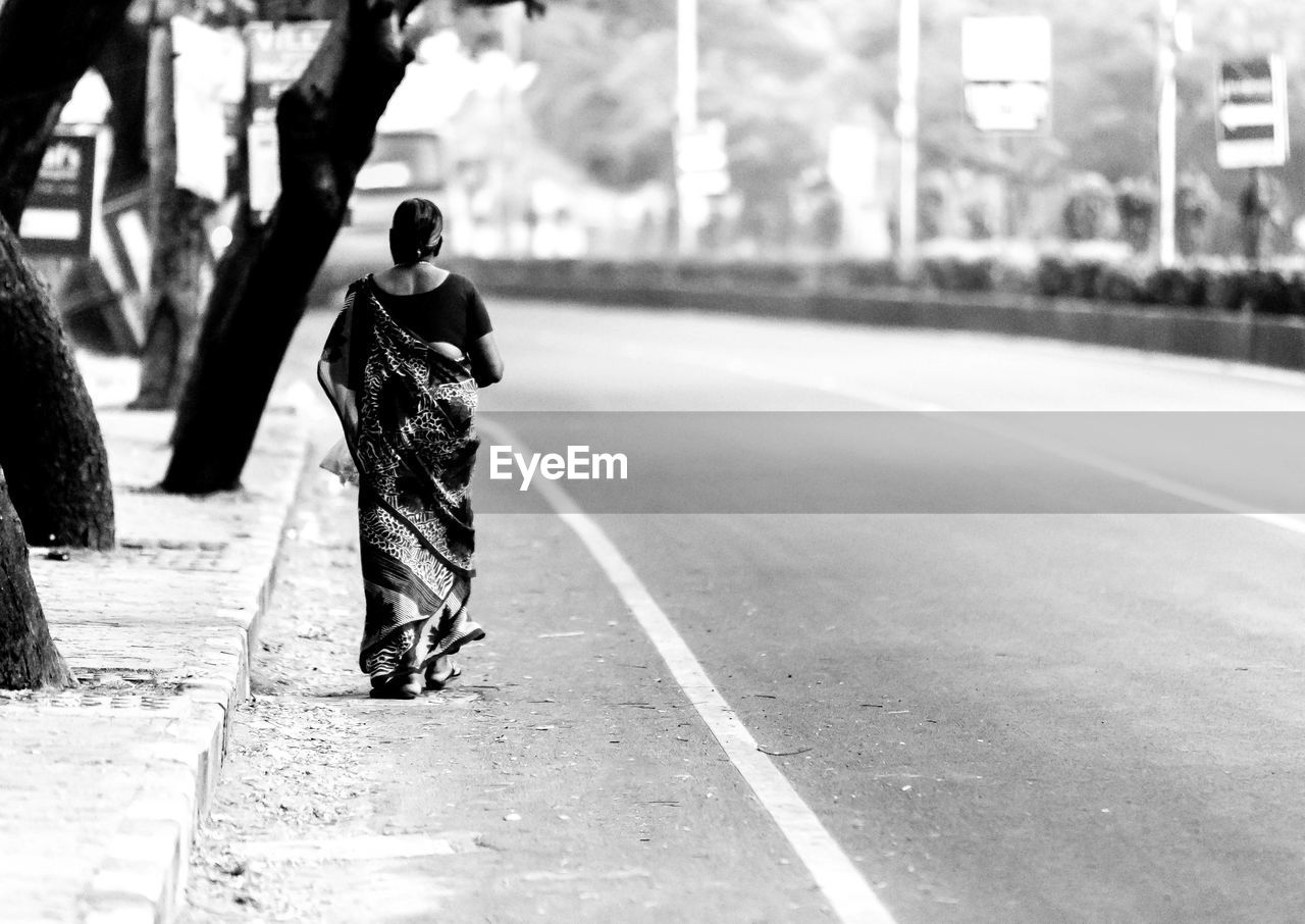 Full length rear view of woman walking on street