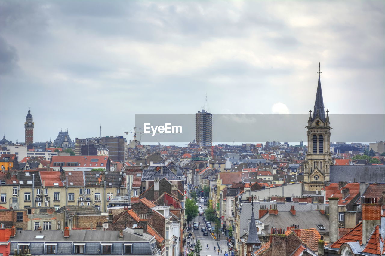 Aerial view of buildings in city against cloudy sky