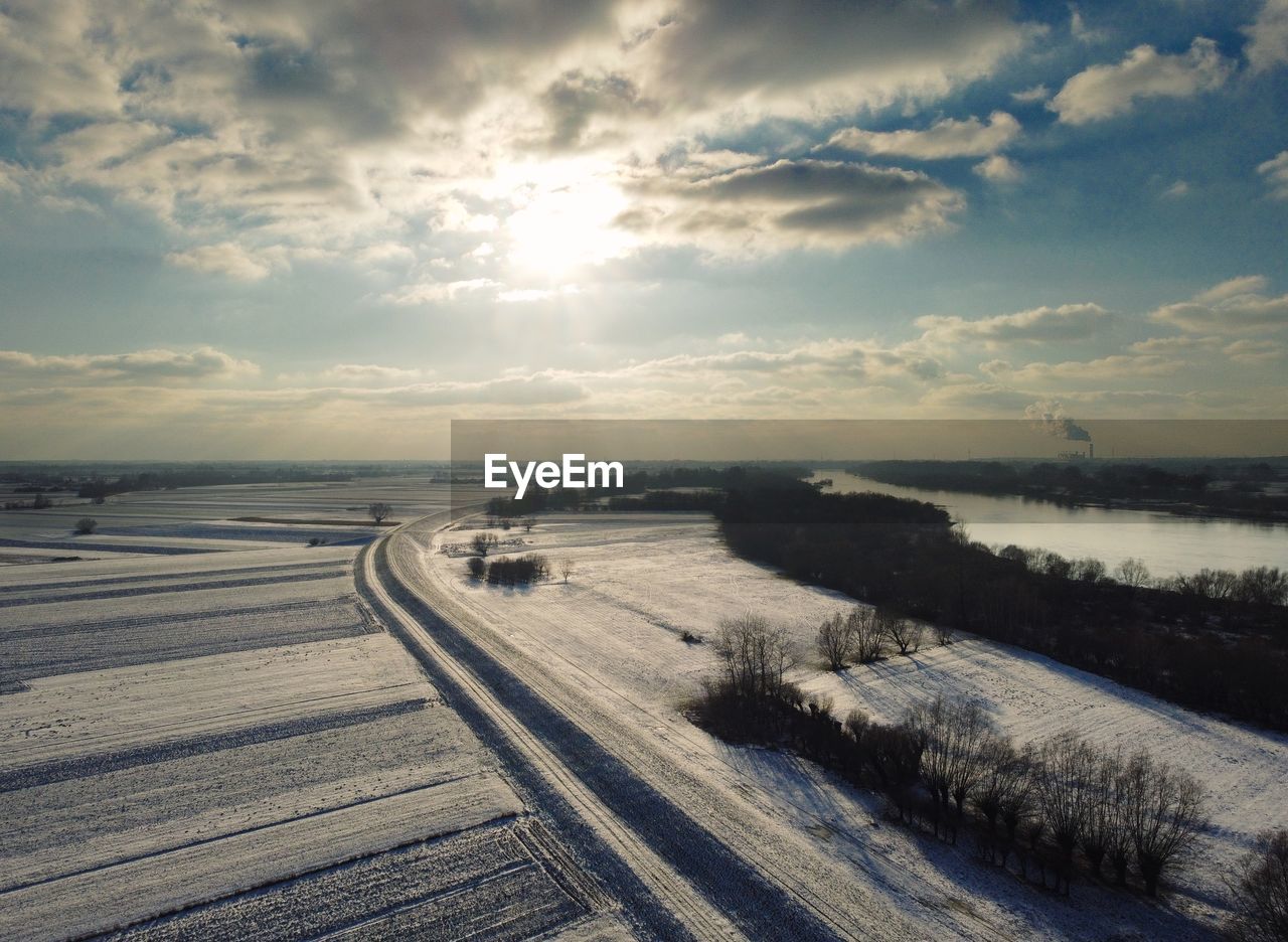 Winter landscape of fields and levees covered with snow against the blue sky
