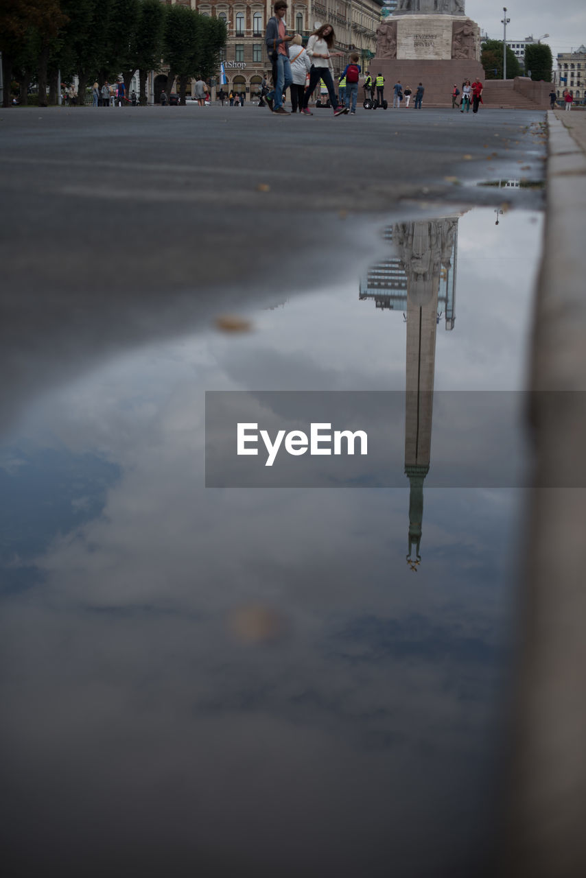 Reflection of sky and column in puddle on street