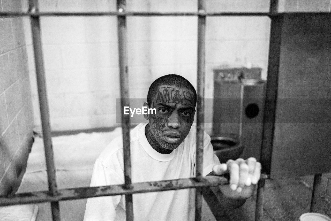 PORTRAIT OF MAN WEARING EYEGLASSES ON FLOOR