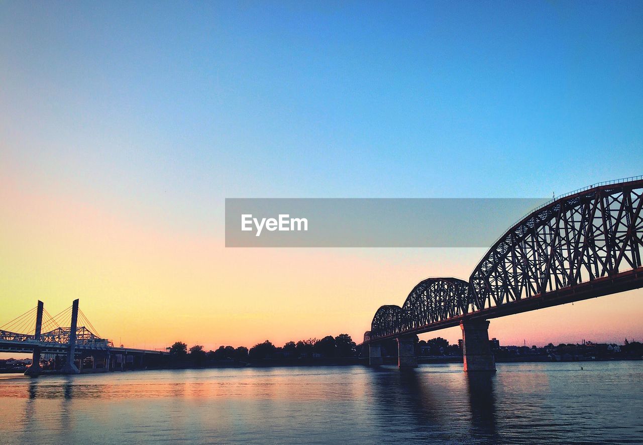 Bridge over river against sky during sunset