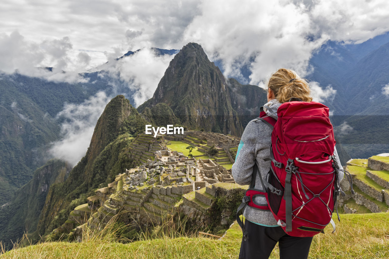 Peru, andes, urubamba valley, tourist with red backpack at machu picchu with mountain huayna picchu