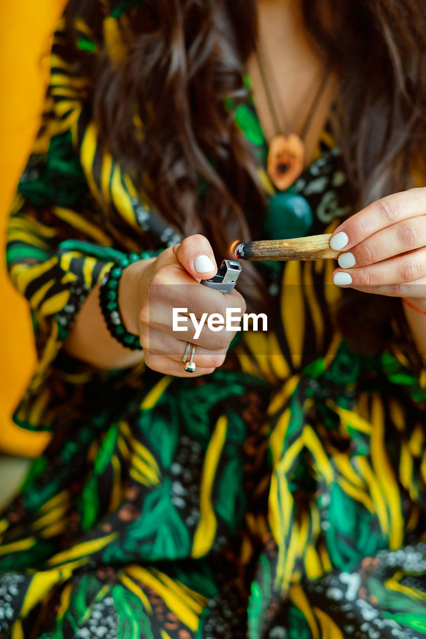 A stick of palo santo tree in the hands of a girl. a woman lights a stick. close up.