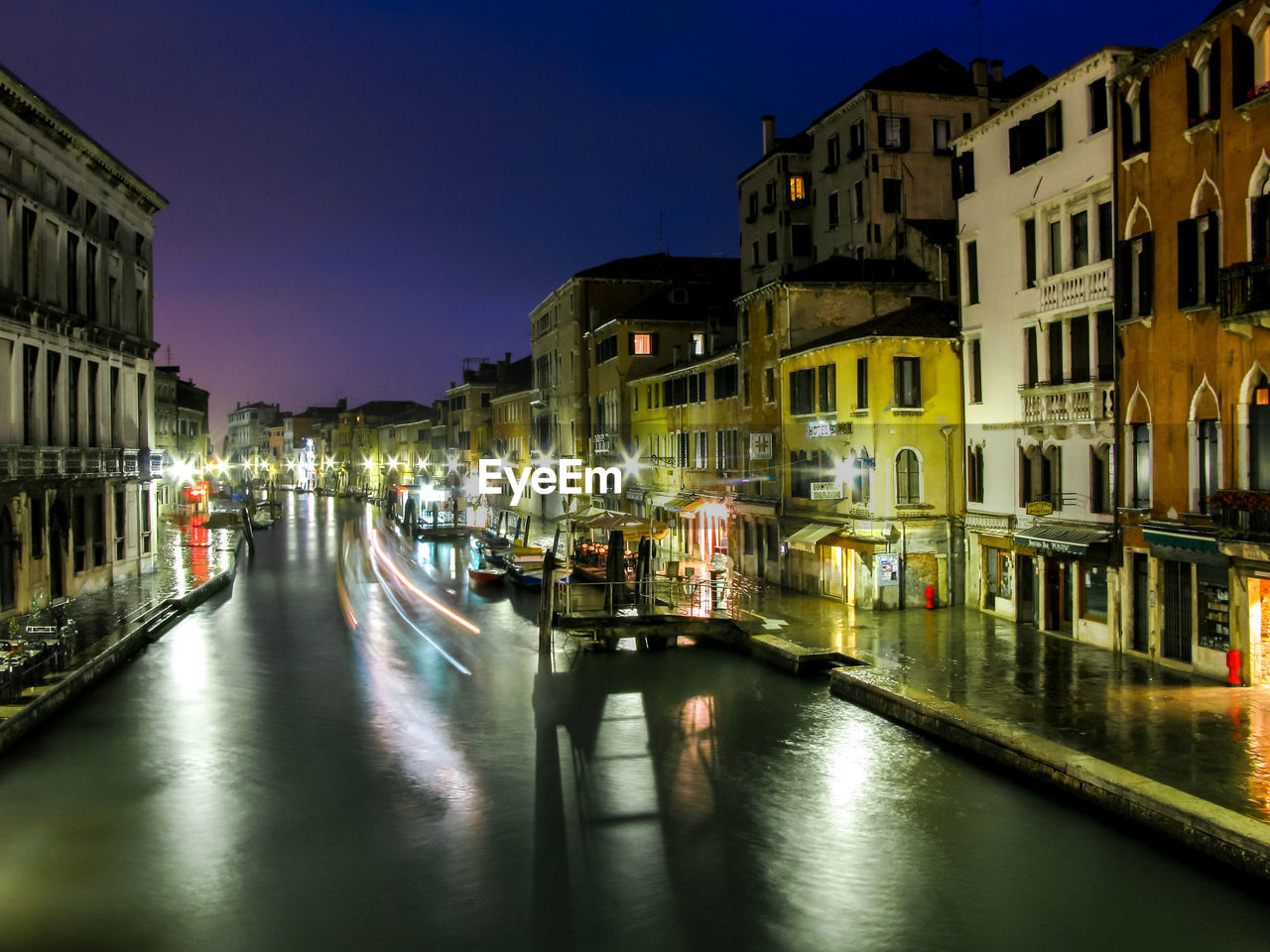 View of boats and old buildings reflected in venice canals at night