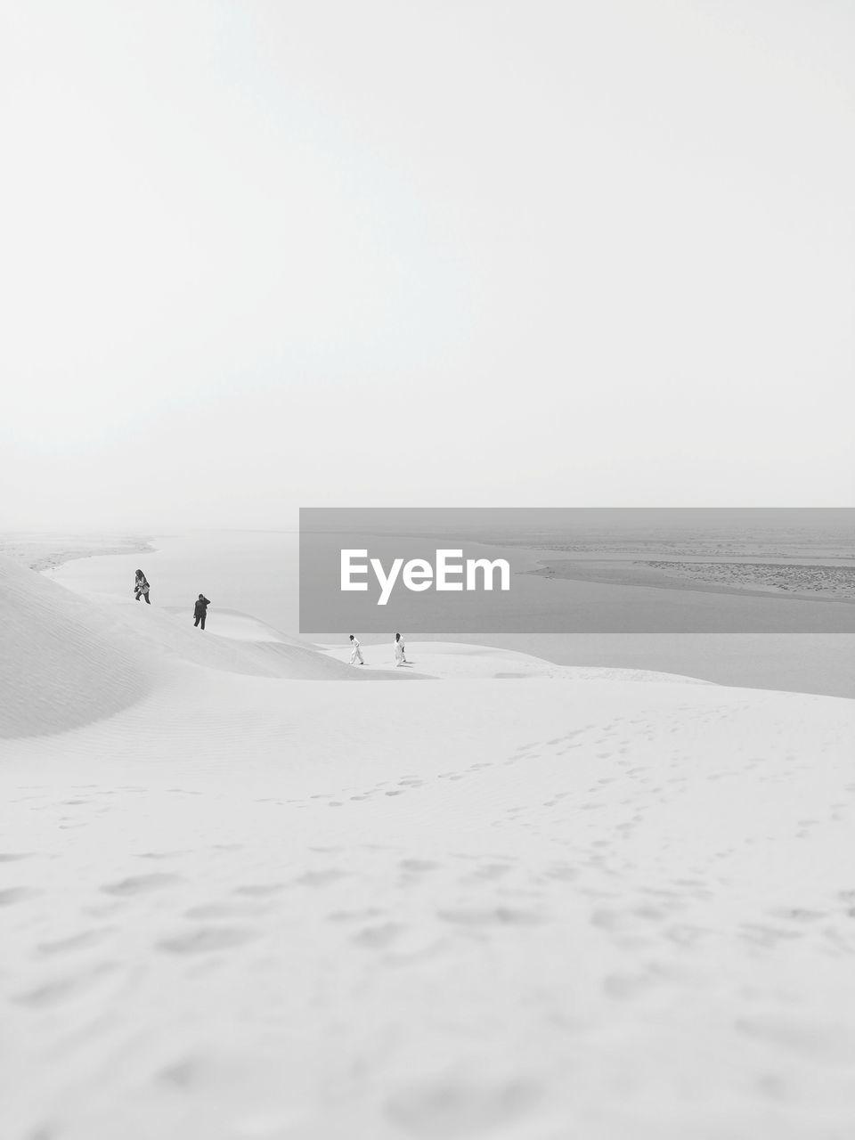 People on sand dune against sky