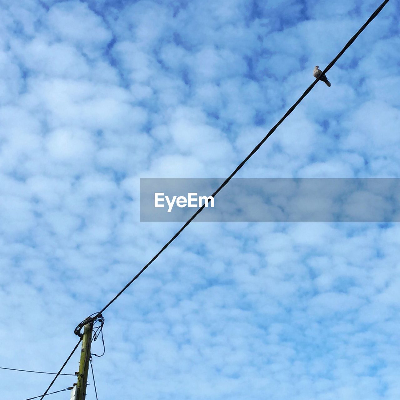 Low angle view of electricity pylon against cloudy sky