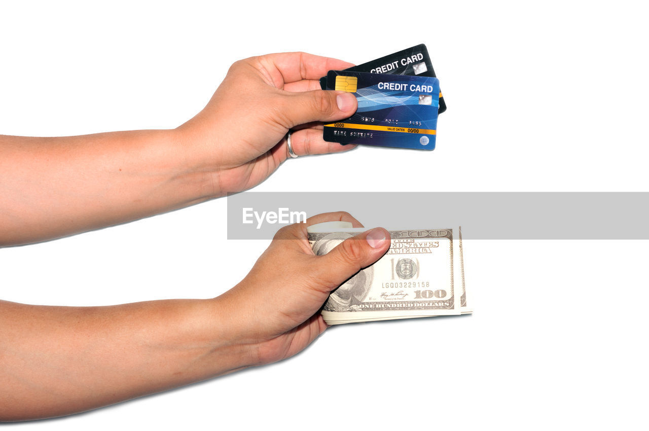 CLOSE-UP OF HAND HOLDING PAPER AGAINST WHITE BACKGROUND