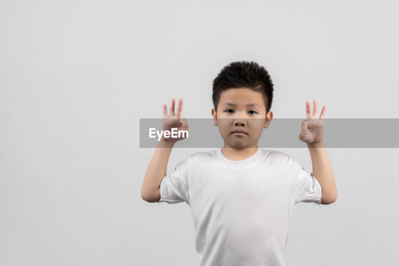 FULL LENGTH PORTRAIT OF BOY STANDING AGAINST WHITE BACKGROUND