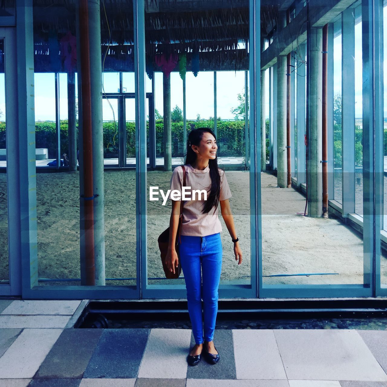 Full length of young woman standing against glass