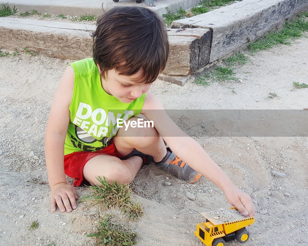 High angle view of boy playing with toy truck on footpath