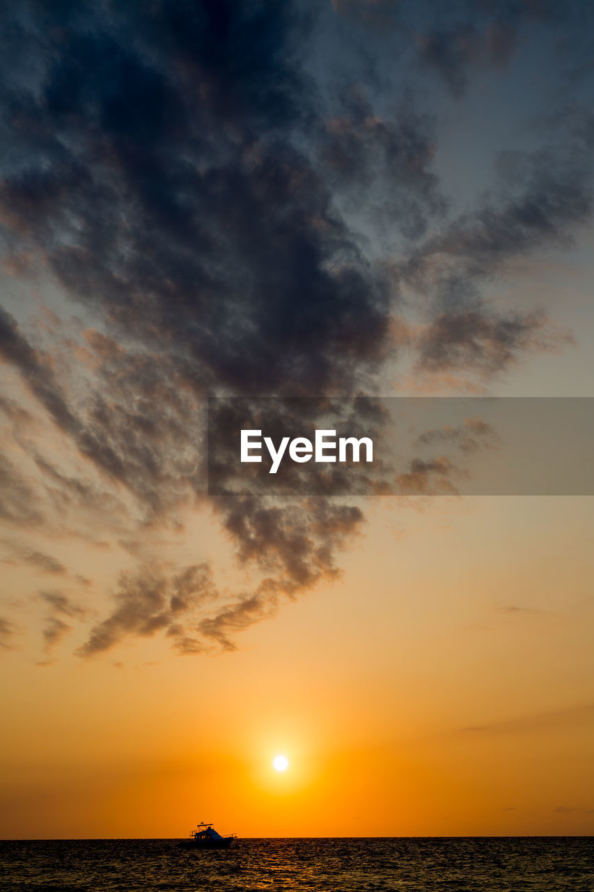 Scenic view of sea against dramatic sky during sunset