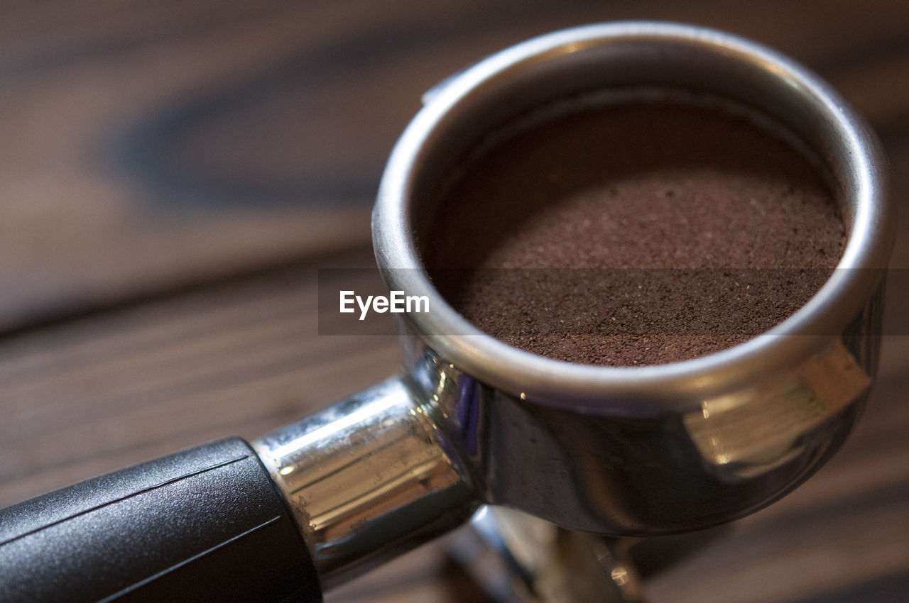 High angle view of ground coffee in container on table at cafe