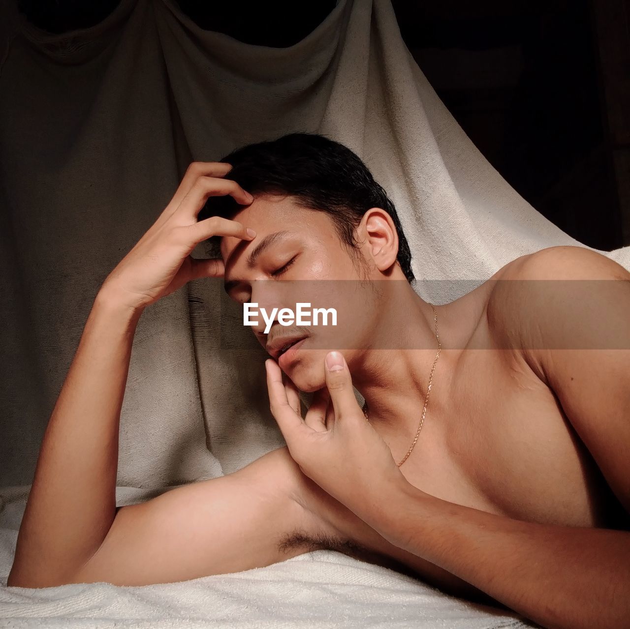 Close-up of shirtless young man lying on bed