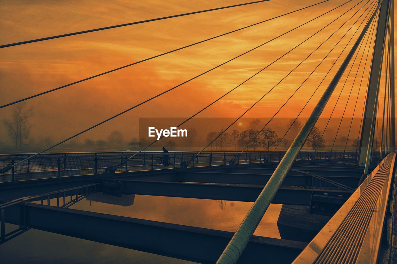 Railroad track on bridge against sky during sunset