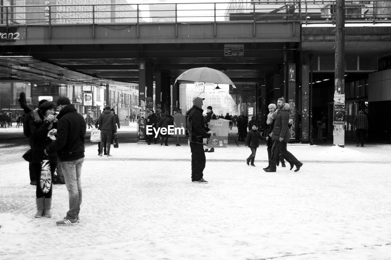 People walking at snowy railroad station