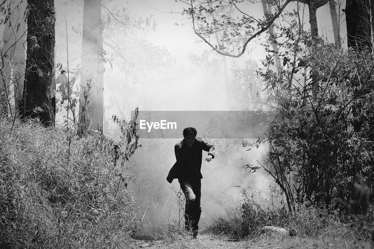 Man walking at forest during foggy weather