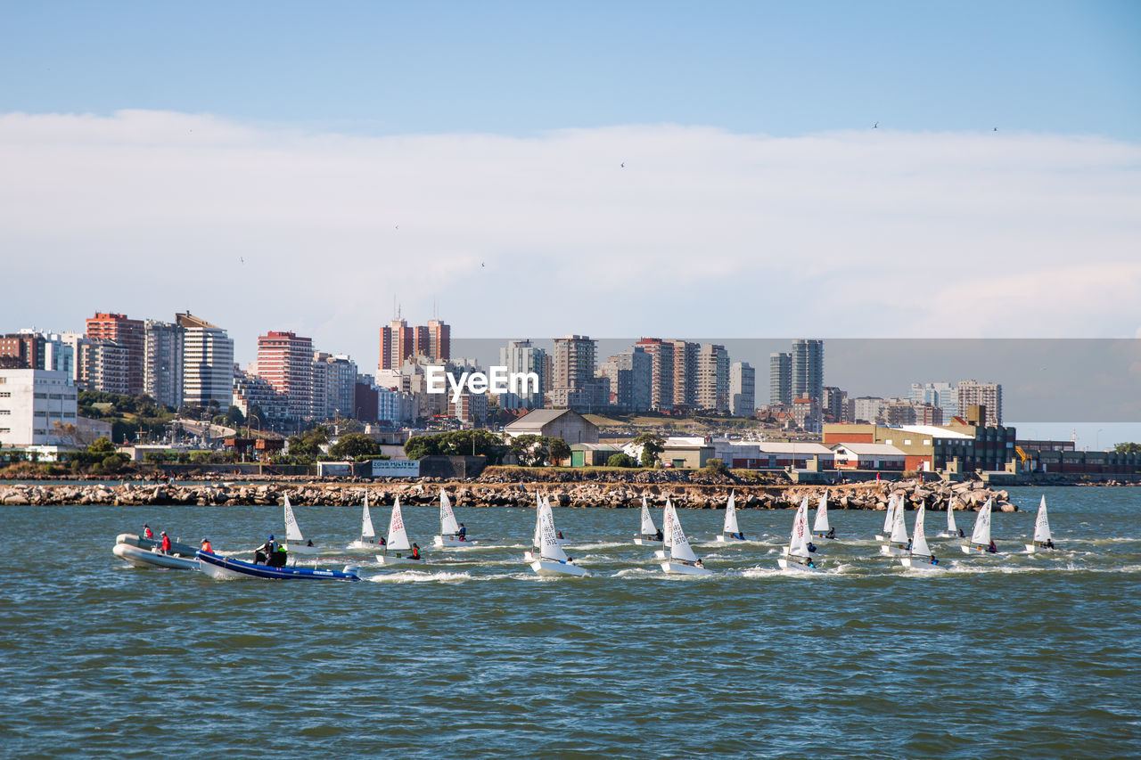 BOATS IN SEA BY BUILDINGS AGAINST SKY