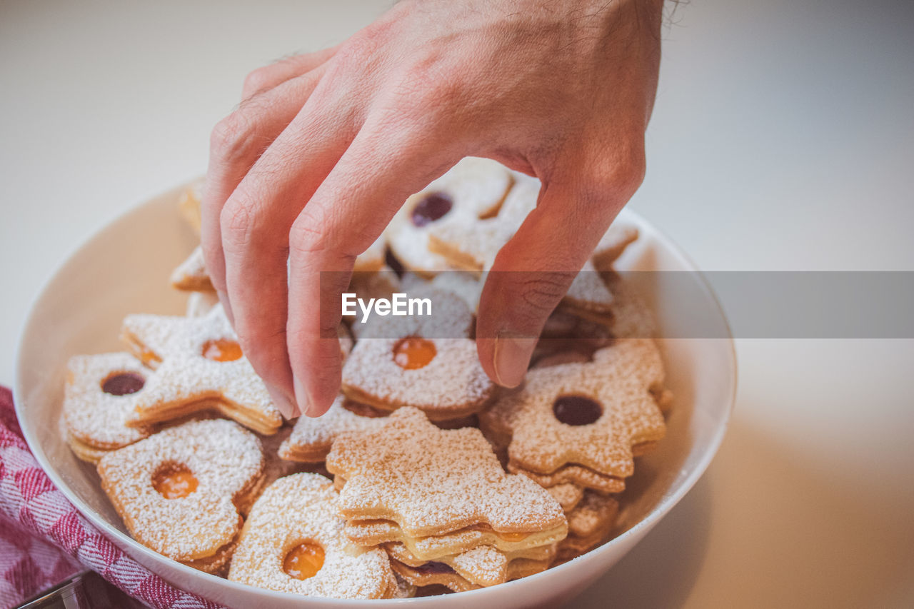 Person taking a cookie from the bowl against white background