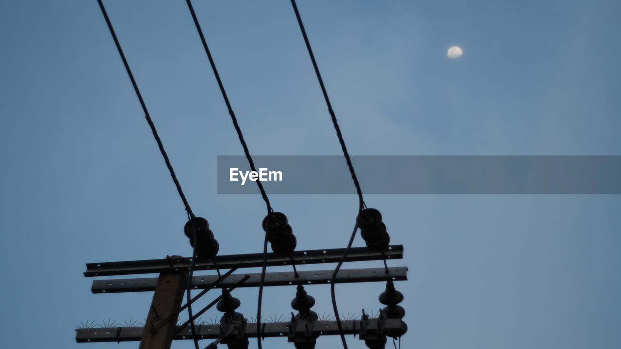 Low angle view of birds perching on cable moon