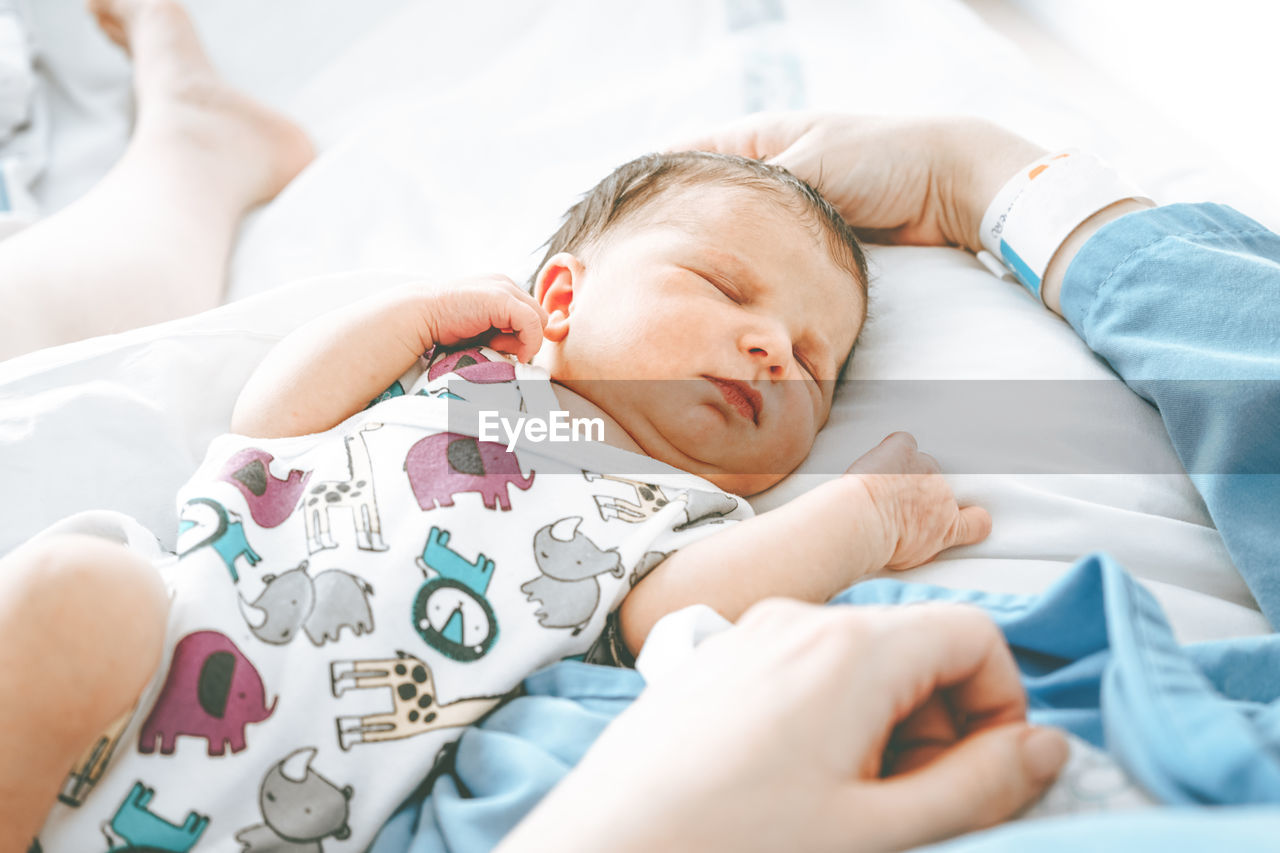 Cute baby sleeping with mother in hospital