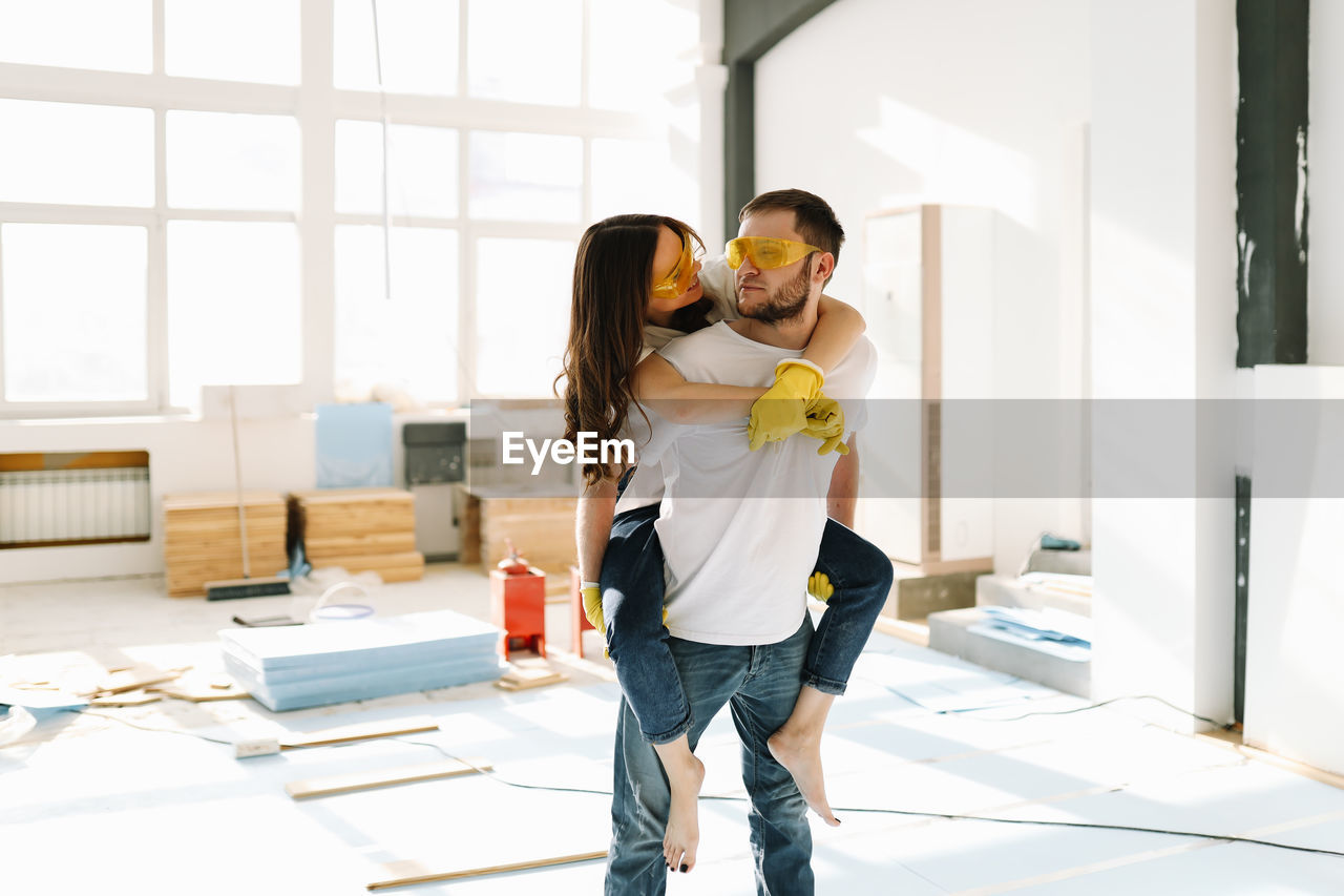 A young couple in love have moved into a new house and are making repairs painting white walls