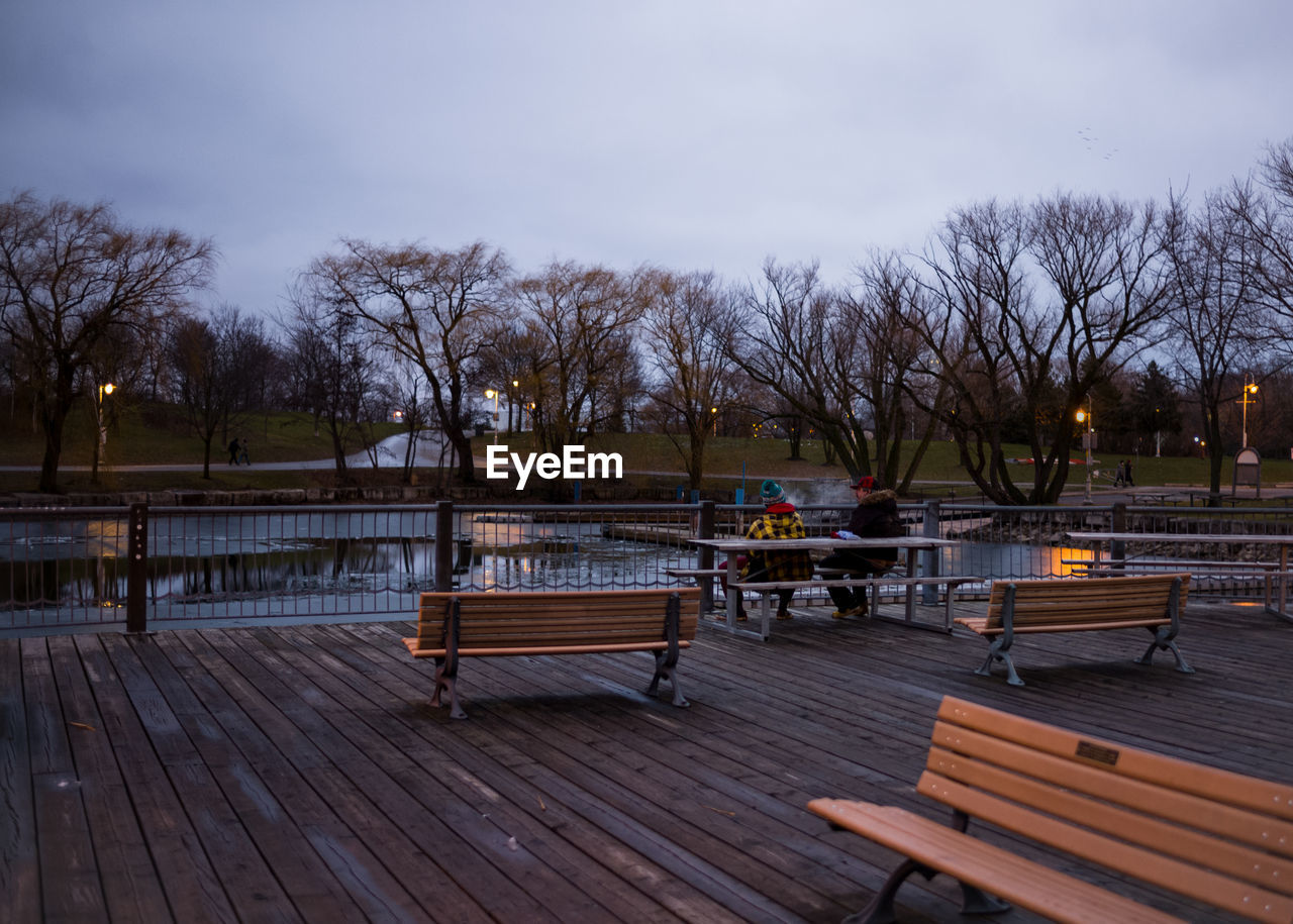 EMPTY BENCH IN PARK AGAINST SKY