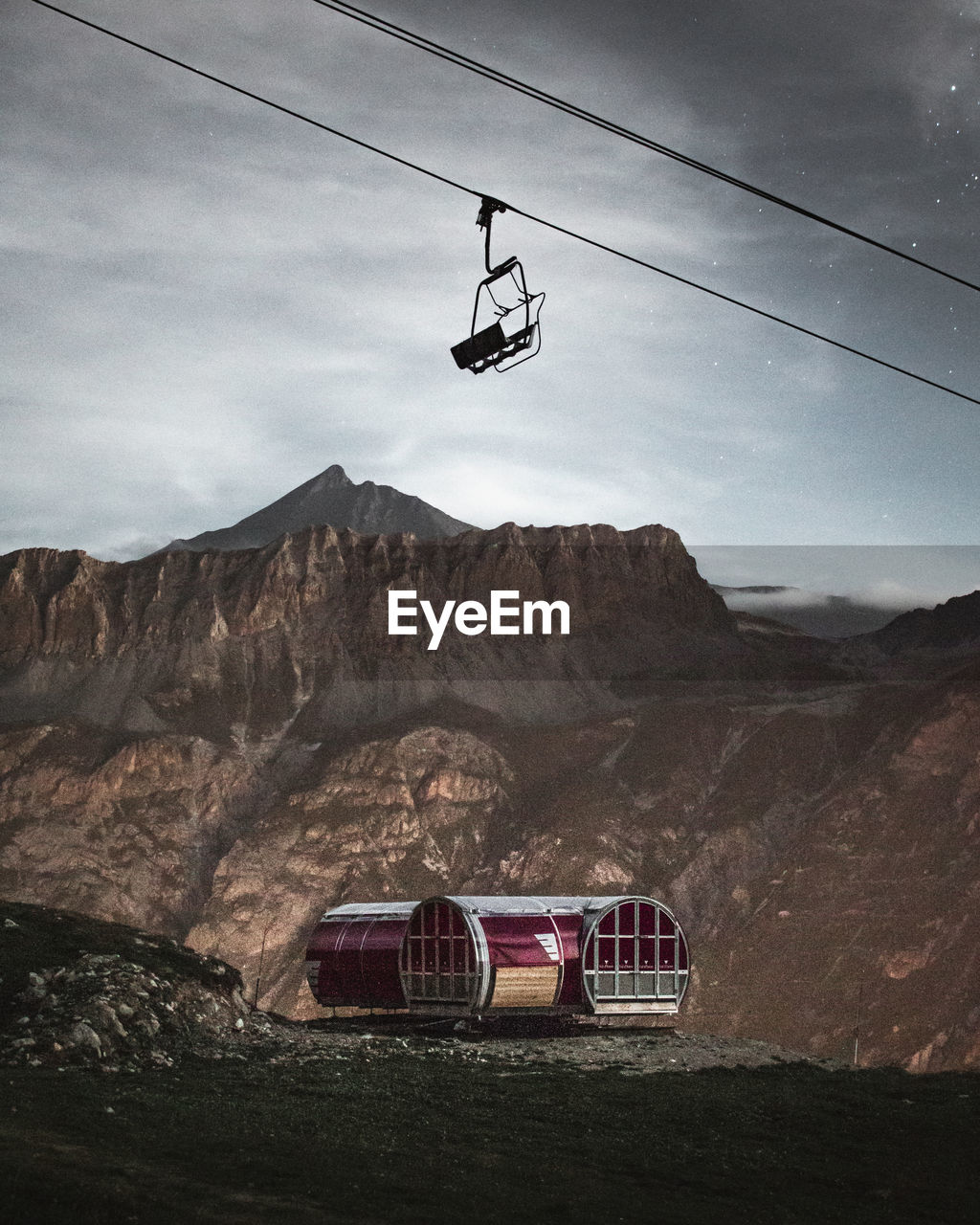 LOW ANGLE VIEW OF OVERHEAD CABLE CAR AGAINST MOUNTAIN