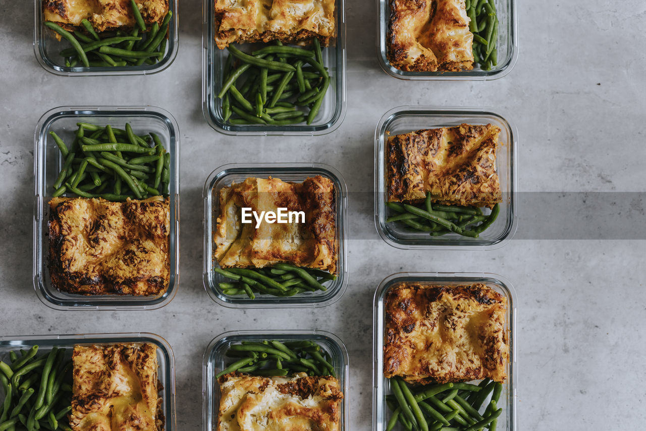 Overhead view of lunch boxes with lasagna and green beans as part of healthy meal prep