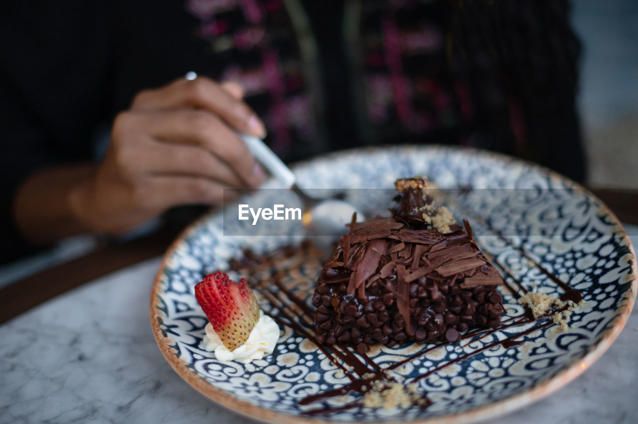 Hands of latina woman eating a chocolate cake in a restaurant